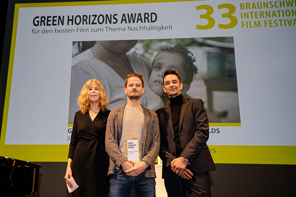 Eine Frau und zwei Männer auf einer Bühne bei einer Preisverleihung auf einem Filmfest