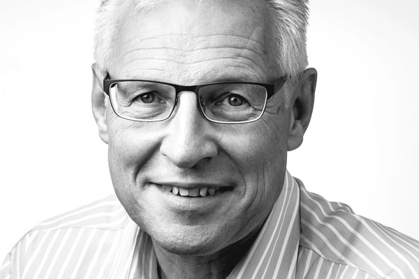 Gesicht eines sympathisch lächelnden Mannes mittleren Alters mit kurzen grauen Haaren und Brille